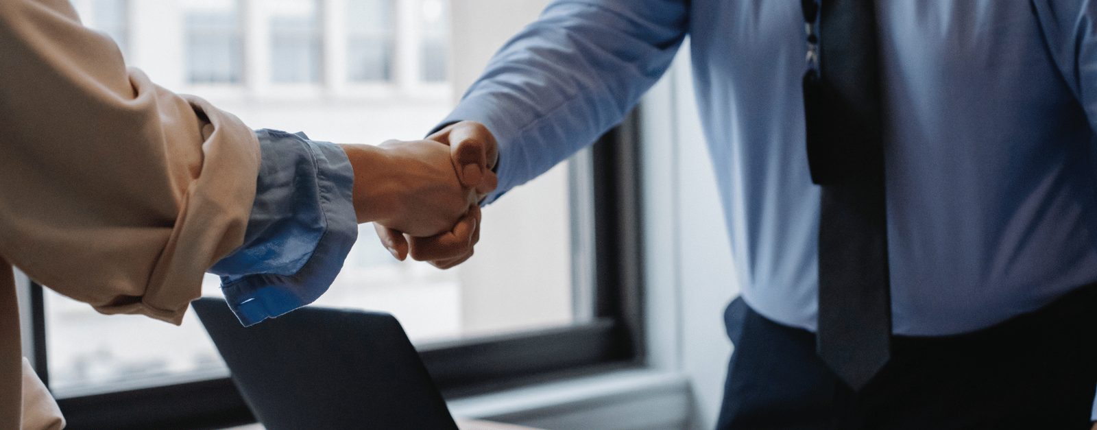 A newly hired LVN shaking hands with a hiring manager after accepting a nursing position